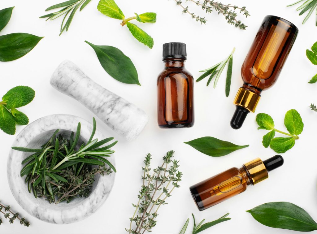 Dropper bottles with oil and mortar with herbs on white table flat lay view