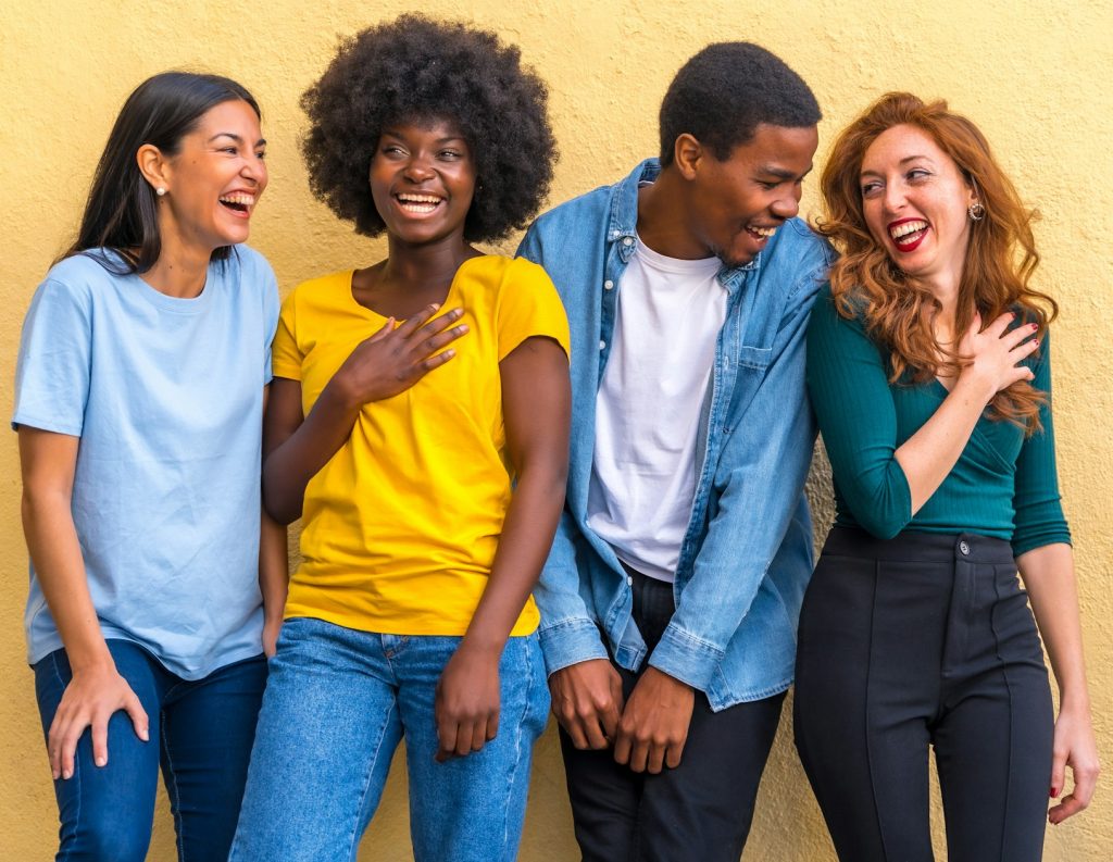 Multi ethnic friends against yellow wall having fun smiling, international youth community